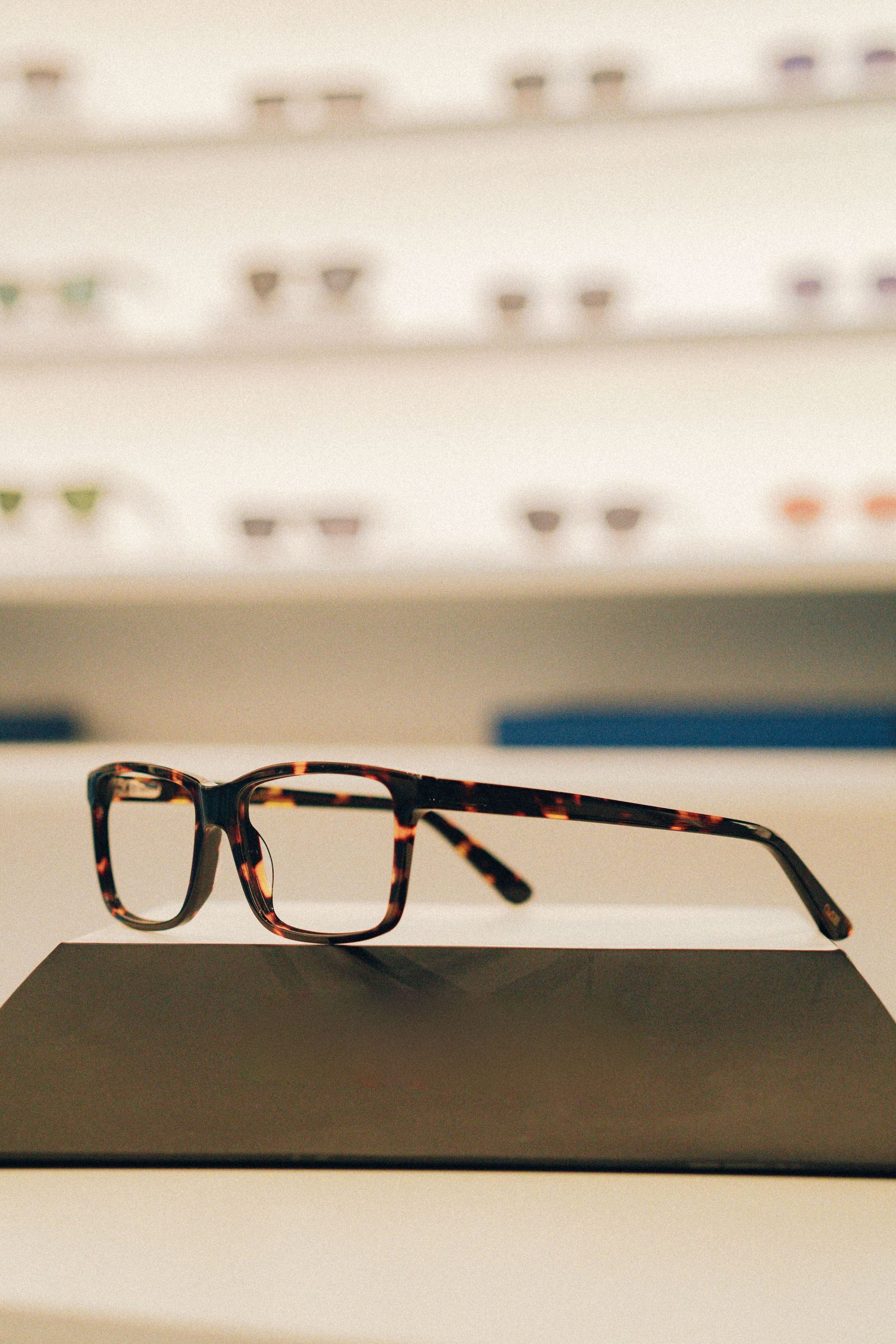 Armações leves em metal prata e dourado apoiadas em suporte de acrílico.