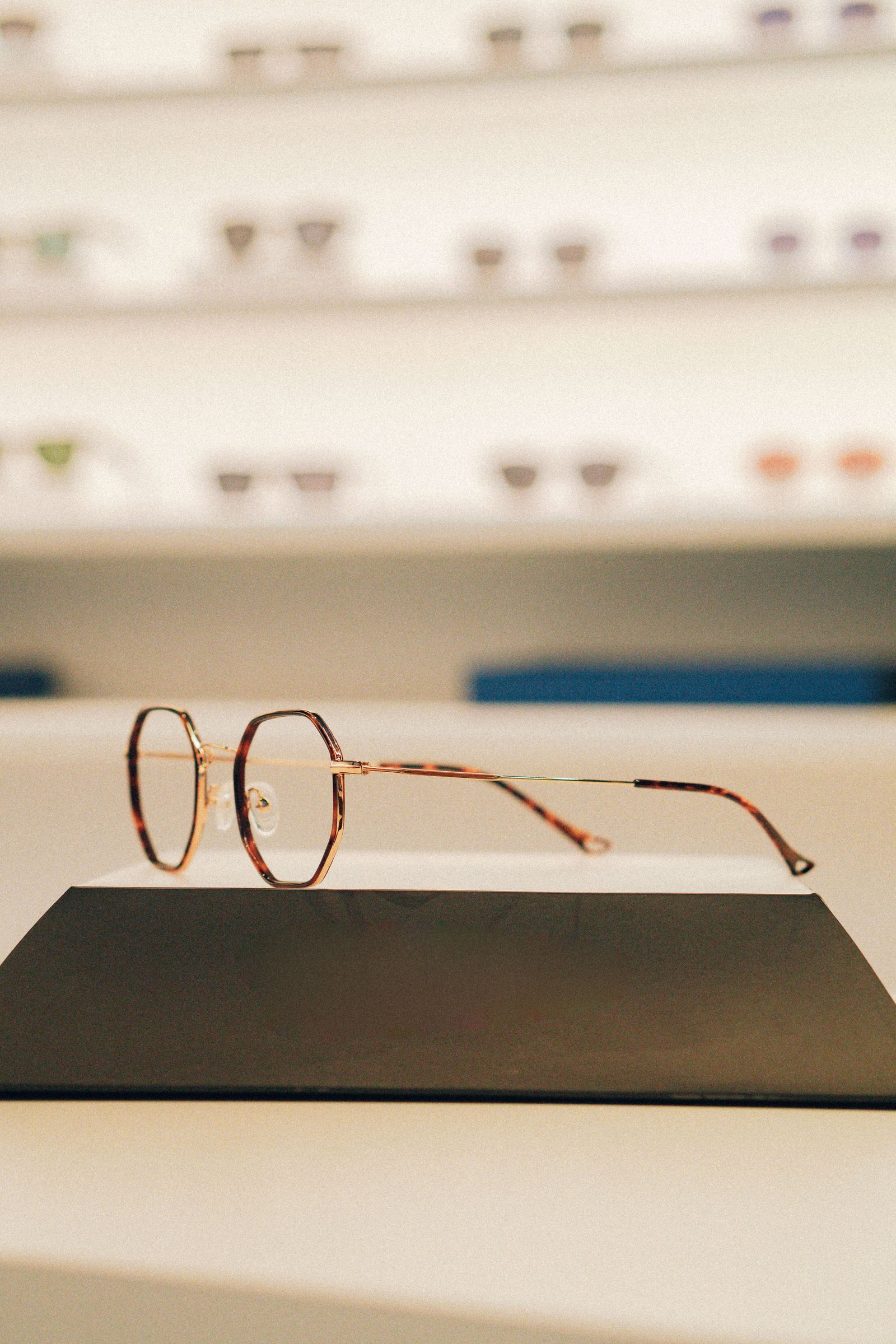 Sequência de armações de óculos de grau em prateleira iluminada da OART.