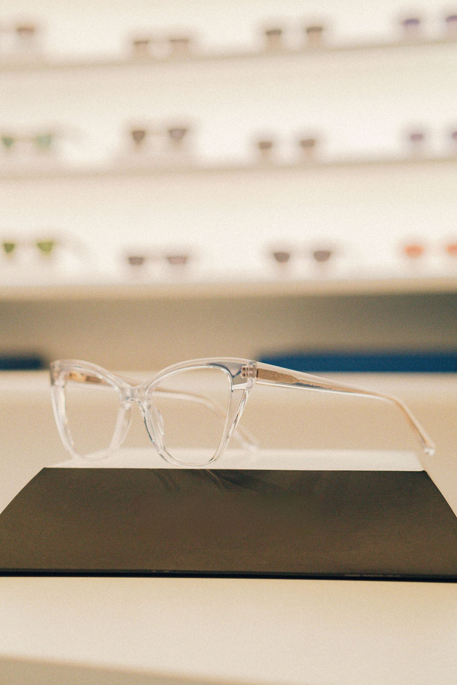 Conjunto de armações de óculos coloridas destacadas contra fundo neutro.