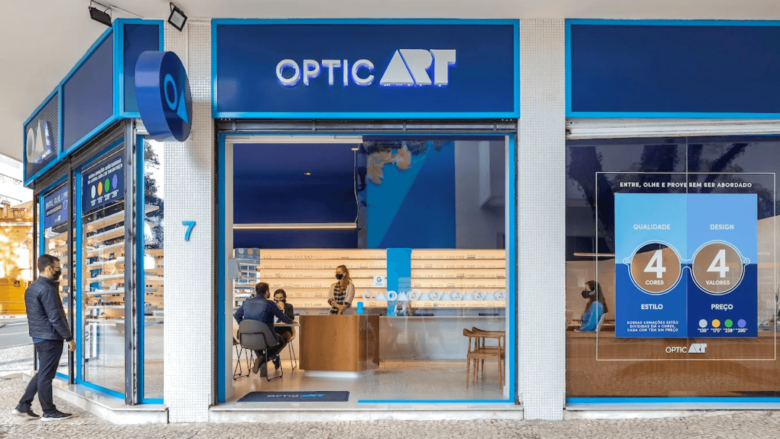 Entrada da OPTIC OART em Curitiba com logo iluminado e balcão de atendimento ao fundo.