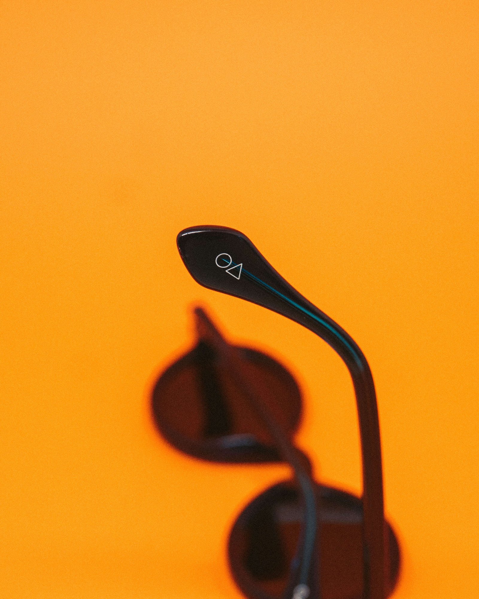 Óculos de sol em acetato marrom com lentes âmbar sobre fundo laranja.