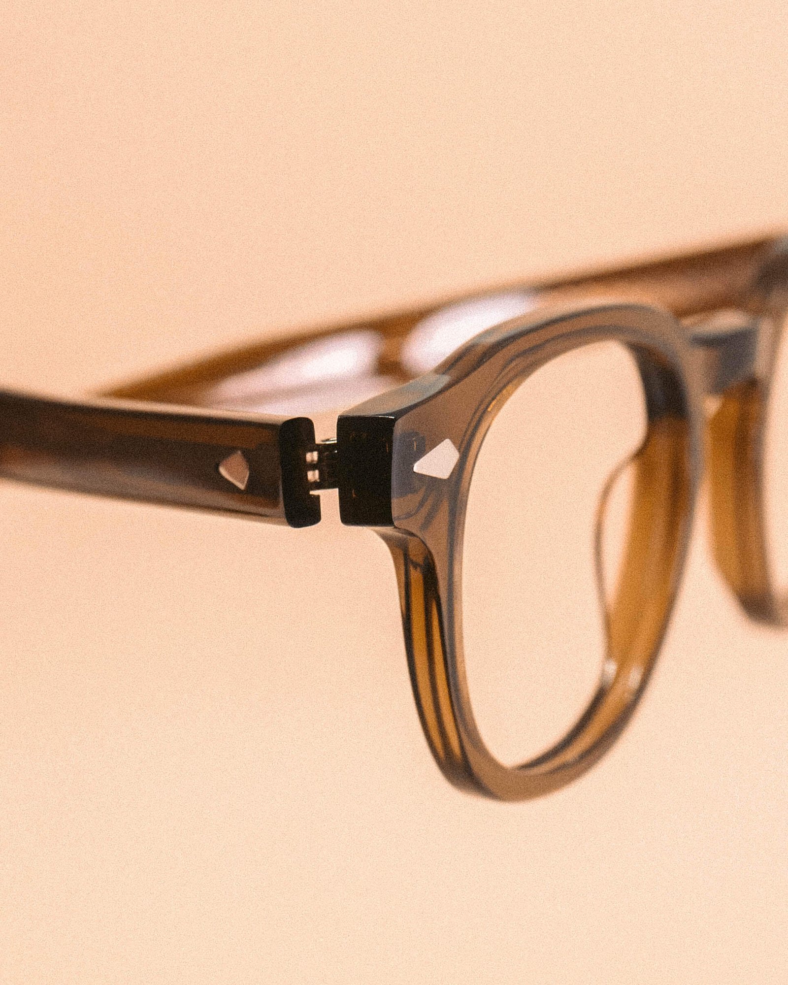 Óculos de sol redondo azul turquesa com lentes escuras em fundo bege.