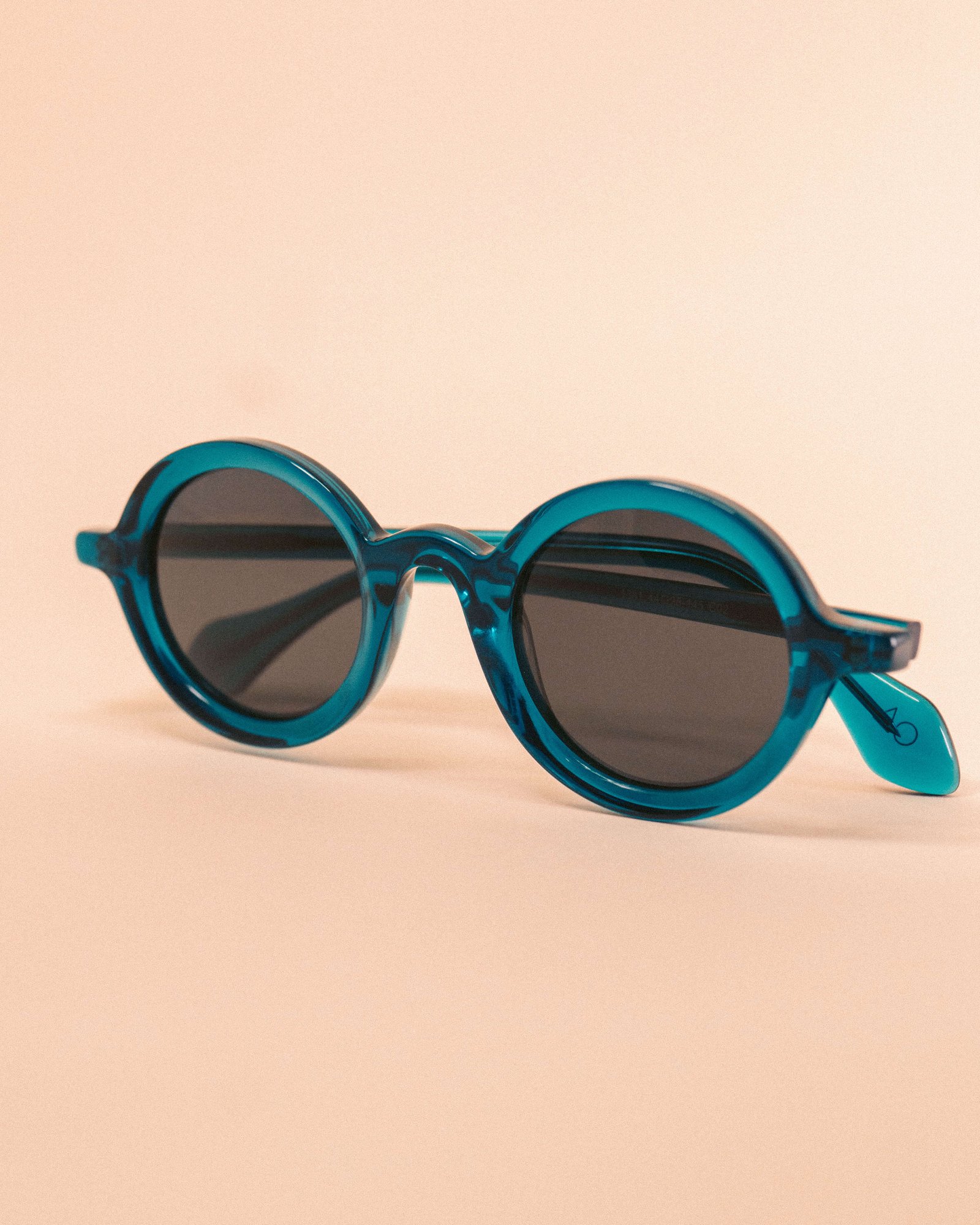 Óculos de sol quadrado marrom com lentes degradê em fundo bege.